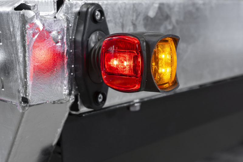 Veiligheidssignalen op een aanhangwagen met rode en oranje lichten.