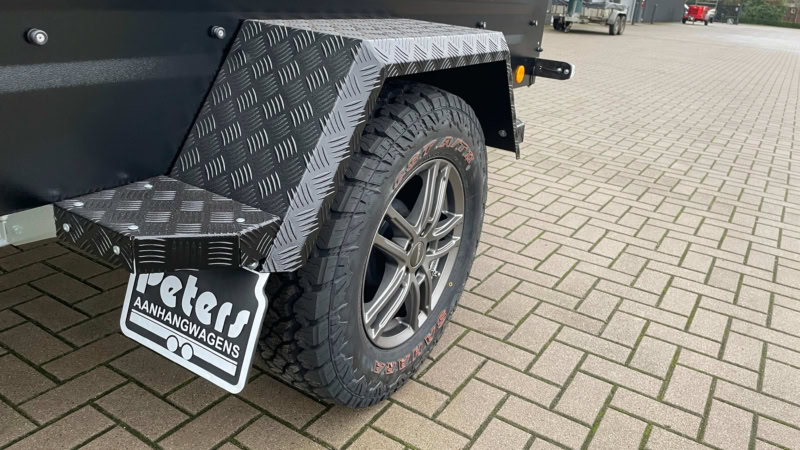 Aanhangwagen met stevige banden en metalen spatbord voor transport.