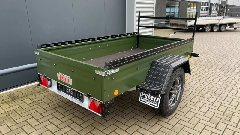 Kleine groene aanhangwagen met laadbak en banden, geschikt voor transport.