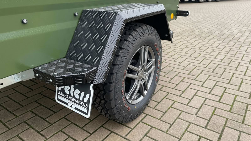 Aanhangwagen met groene kleur, stevige banden en zwart spatbord voor diverse transportdoeleinden.